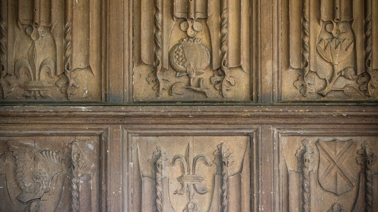 Close up of a section of the carved panels on The Vyne's Tudor gallery showing several emblems